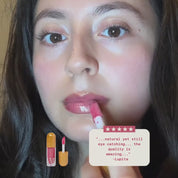 A woman swatching oro lip gloss on her lips while a customer review is displayed saying "...natural yet still eye catching... the quality is amazing..." by Lupita
